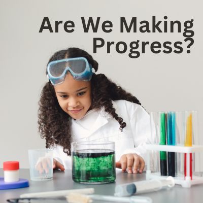 Female, black elementary student wearing a lab coat and learning about STEM.