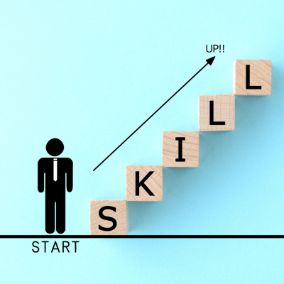 Graphic of a professional next to scrabble tiles that spell SKILLS. The tiles are arranged to look like a staircase indicating professional career progression.